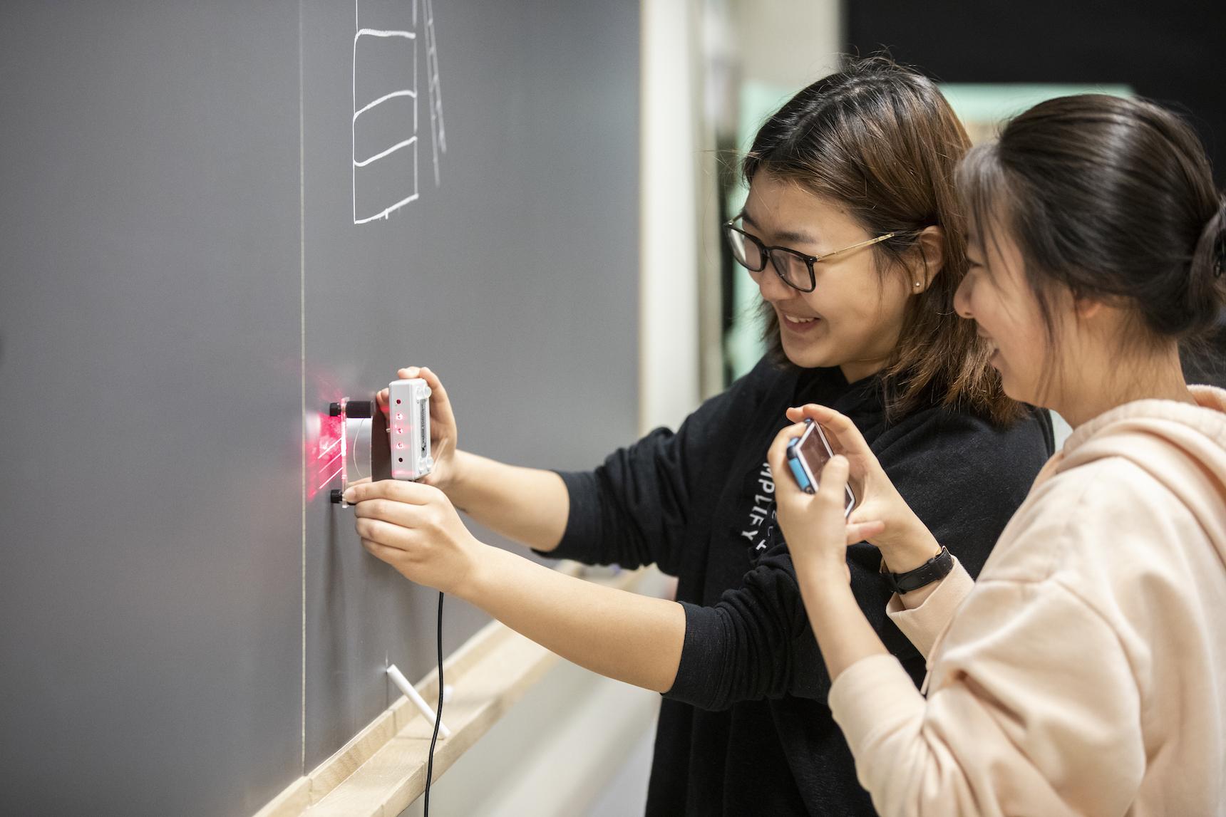 Two physics students work with a laser device.